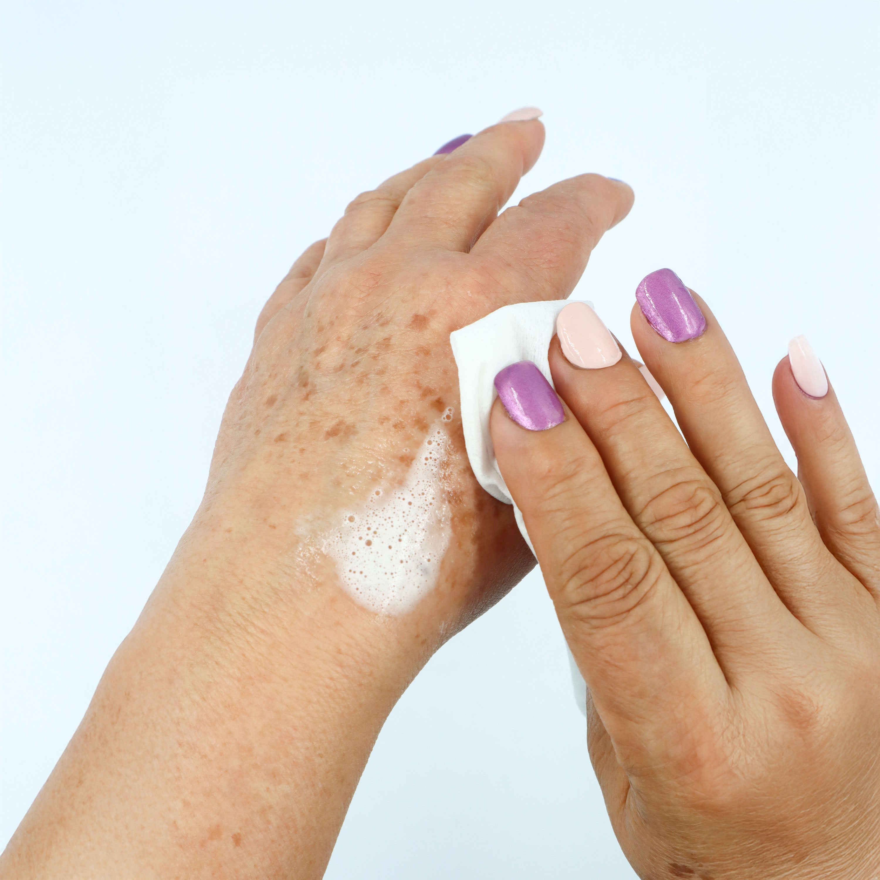 Mano de persona mayor con espuma de un paño de Geriderm Baño Fácil