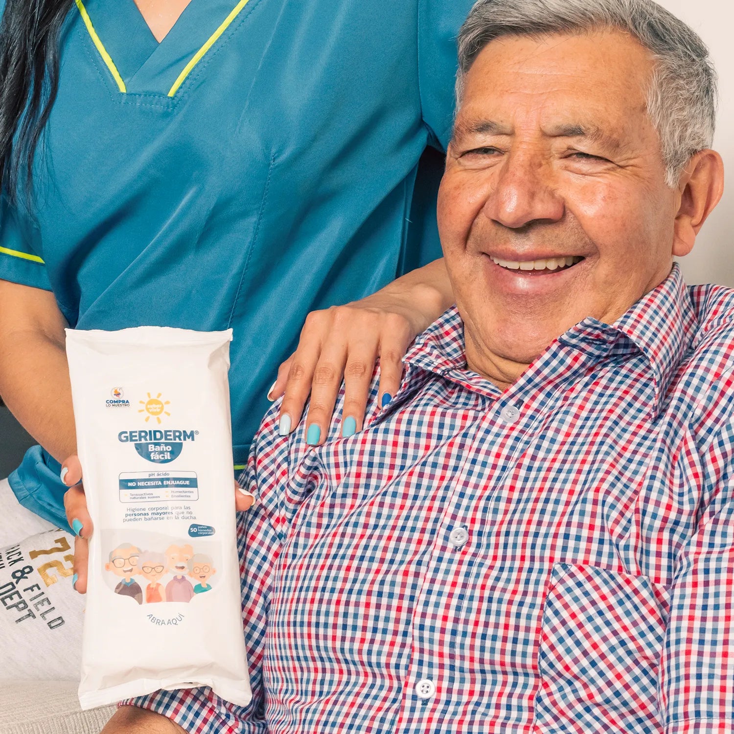 Hombre mayor junto a enfermera sosteniendo un empaque de pañitos húmedos para baño de paciente en cama 