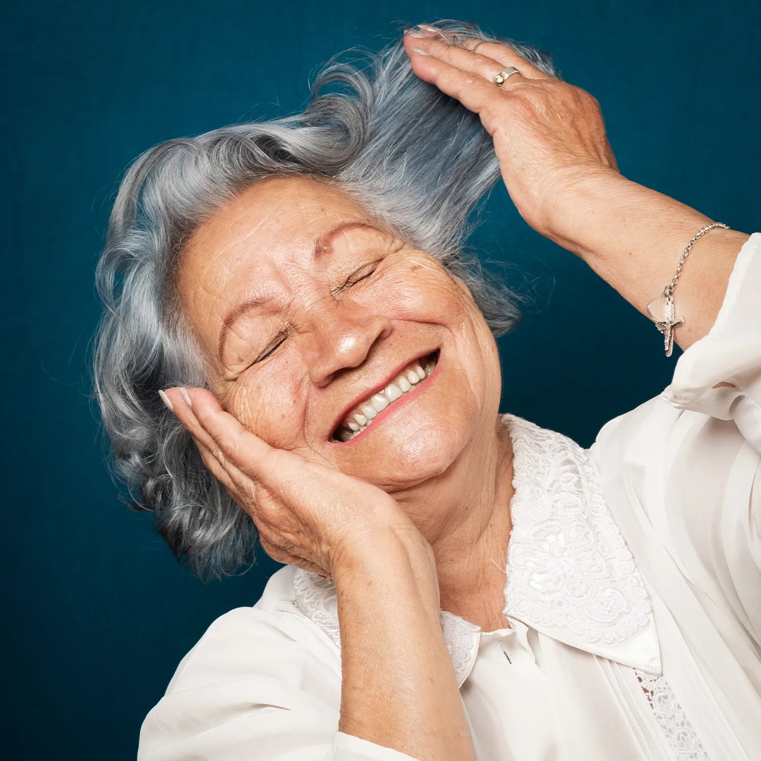 Mujer mayor tacándose suavemente el cabello después de usar champú seco Geriderm 