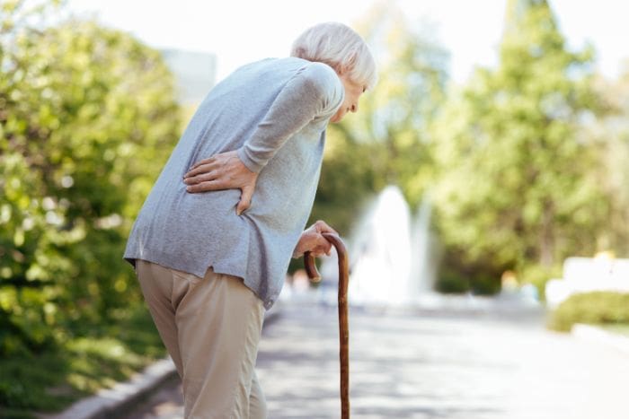 Mujer mayor con bastón y dolor de cadera